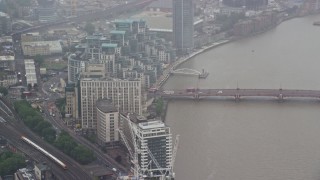 AX115_061E - 5.5K aerial stock footage of MI6 Building and Vauxhall Bridge over the River Thames in the rain, London, England