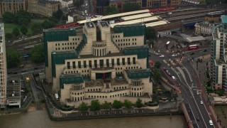 AX115_066 - 5.5K aerial stock footage of orbiting the MI6 Building by busy streets in the rain, London, England