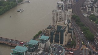 AX115_069E - 5.5K aerial stock footage of orbiting the MI6 Building revealing skyscraper in the rain, London, England