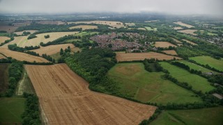 AX115_303E - 5.5K aerial stock footage fly over farmland and past rural homes in a village, Coulsdon, England