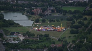 AX116_007 - 5.5K aerial stock footage of flying by small fair at Burgess Park, London, England, twilight