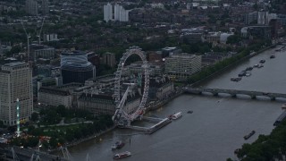 AX116_057E - 5.5K aerial stock footage of flying by London Eye and Westminster Bridge over River Thames, London, England, twilight