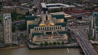 AX116_065 - 5.5K aerial stock footage of flying by MI6 Building by River Thames, London, England, twilight