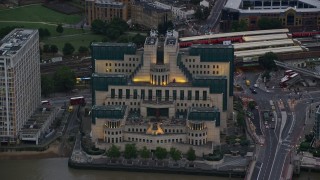 AX116_065E - 5.5K aerial stock footage of flying by MI6 Building by River Thames, London, England, twilight