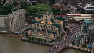 AX116_067 - 5.5K aerial stock footage of flying away from MI6 Building by River Thames, London, England, twilight