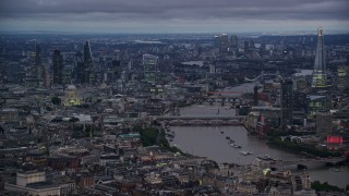 AX116_105E - 5.5K aerial stock footage of bridges spanning River Thames near skyscrapers, London, England, night