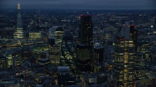 AX116_166E - 5.5K aerial stock footage of The Gherkin skyscraper, seen from near Heron Tower, London, England, night