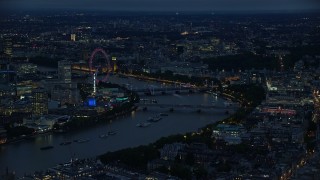 AX116_174 - 5.5K aerial stock footage of approaching bridges spanning River Thames and London Eye, London, England, night