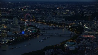 AX116_175 - 5.5K aerial stock footage of an approach to London Eye by bridges over River Thames, London, England, night