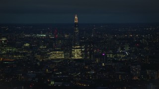 AX116_198E - 5.5K aerial stock footage of The Shard towering over city buildings, London, England, night