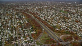 AX117_008E - 5.5K aerial stock footage of suburbs and freeway with light traffic in Autumn, Massapequa, New York