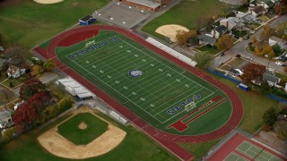 AX117_025E - 5.5K stock footage aerial video of a high school track and football field in Autumn, Merrick, New York