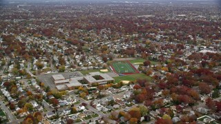 AX117_030E - 5.5K aerial stock footage of a high school in the suburbs in Autumn, Merrick, New York