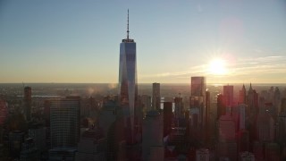 AX118_099 - 5.5K aerial stock footage of orbiting around Freedom Tower with view of rising sun in Lower Manhattan, New York City