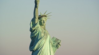 AX118_107E - 5.5K aerial stock footage of a close-up view of the Statue of Liberty at sunrise in New York