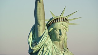 AX118_115E - 5.5K aerial stock footage of orbiting the Statue of Liberty monument at sunrise in New York