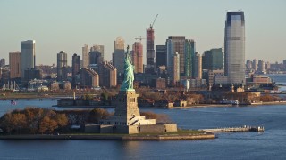 AX118_124E - 5.5K aerial stock footage of orbiting the front of the Statue of Liberty monument at sunrise in New York