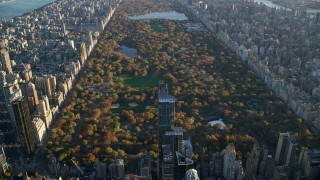 AX118_188 - 5.5K stock footage aerial video approach Central Park with Autumn leaves at sunrise in New York City