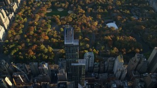 AX118_189 - 5.5K stock footage aerial video approach One57 skyscraper and Central Park with Autumn leaves at sunrise in New York City