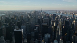AX118_197E - 5.5K aerial stock footage of Midtown skyscrapers at sunrise in New York City, with view of distant Lower Manhattan