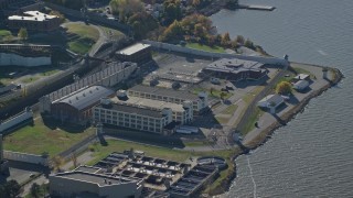 AX119_118E - 5.5K aerial stock footage of orbiting riverfront Sing Sing Prison in Autumn, Ossining, New York