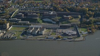 AX119_121E - 5.5K aerial stock footage orbit Sing Sing Prison in Autumn, seen from the river, Ossining, New York