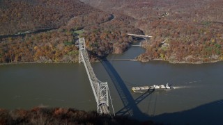 AX119_151E - 5.5K aerial stock footage of flying over forest in Autumn, reveal oil tanker sailing toward a bridge, Westchester County, New York