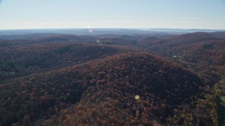 AX119_185E - 5.5K aerial stock footage approaching hills with forests in Autumn, Garrison, New York