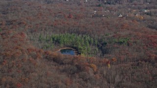AX119_192E - 5.5K aerial stock footage of a pond and forest in Autumn, Garrison, New York
