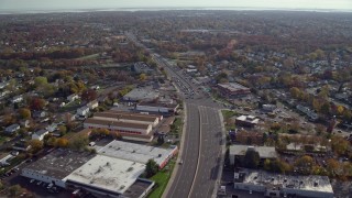 AX120_001E - 5.5K aerial stock footage of warehouses on a wide street in Autumn, Farmingdale, New York