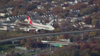 AX120_060E - 5.5K aerial stock footage of a cargo plane descending toward JFK Airport, New York in Autumn