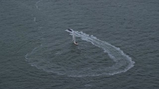 AX121_015 - 5.5K aerial stock footage of a harbor police boat speeding away from sailboat in New York Harbor at twilight