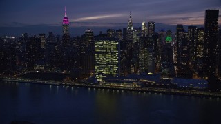 AX121_144E - 5.5K aerial stock footage approach UN Building in Midtown at Night from East River, New York City