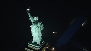 AX121_168E - 5.5K aerial stock footage a slow orbit above Statue of Liberty at Night in New York