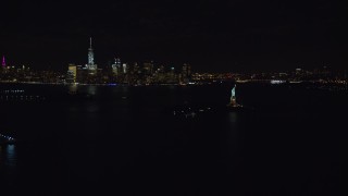 AX122_009E - 5.5K aerial stock footage of a wide orbit of Statue of Liberty and Lower Manhattan at Night, New York