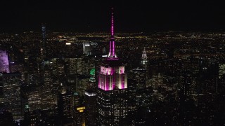 AX122_085E - 5.5K aerial stock footage orbit the rooftop of Empire State Building as it lights up at Night in Midtown, New York City