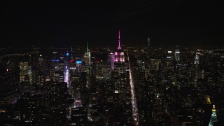 AX122_106E - 5.5K aerial stock footage approach Empire State Building with pink and white lights at Night in Midtown, NYC
