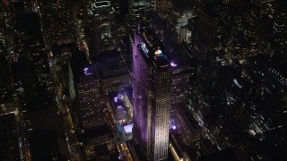 AX122_202E - 5.5K stock footage aerial video of circling around Rockefeller Center with ice rink at Night in Midtown, NYC