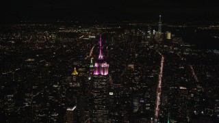 AX122_213 - 5.5K stock footage aerial video orbit Empire State Building with view of Lower Manhattan at Night, New York City