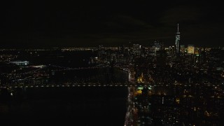 AX122_258 - 5.5K aerial stock footage of approaching the Manhattan and Brooklyn Bridge in Lower Manhattan at Night in NYC