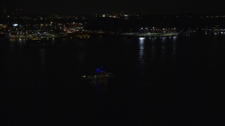 AX123_001 - 5.5K aerial stock footage of tracking a small boat on the Hudson River at Night, Union City, New Jersey