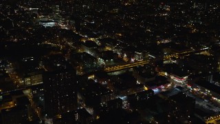 AX123_032 - 5.5K aerial stock footage fly over apartment buildings by elevated rail tracks at Night in Harlem, New York City