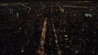 AX123_055 - 5.5K aerial stock footage of high-rises and streets of Upper East Side at Night in NYC