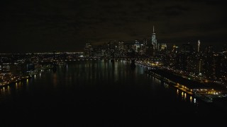 AX123_101E - 5.5K aerial stock footage approach Manhattan Bridge and Lower Manhattan skyline at Night in New York City