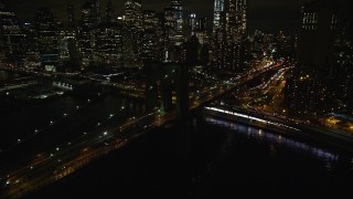 AX123_105E - 5.5K stock footage aerial video of flying toward the Lower Manhattan skyline and the Brooklyn Bridge at night in NYC