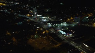AX123_159E - 5.5K aerial stock footage approach shops and restaurants at Night in West Hempstead, New York