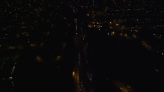 AX123_167E - 5.5K aerial stock footage of a reverse view of Southern State Parkway through Uniondale at Night in New York