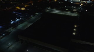 AX123_189E - 5.5K aerial stock footage approach dark warehouse at Night in Farmingdale, New York