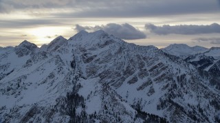 AX124_058 - 5.5K stock footage aerial video of Wasatch Range mountain peaks with winter snow at sunrise in Utah