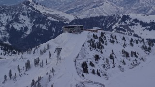 AX124_072E - 5.5K aerial stock footage a ski lift on snowy Hidden Peak at Snowbird Ski Resort at sunrise in Utah